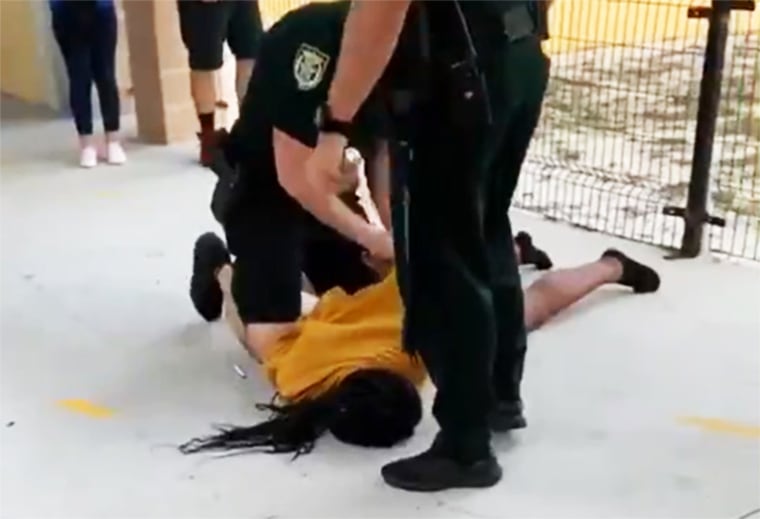 A school resource officer detains a student after slamming her to the ground at Liberty High School in Osceola, Fla., on Jan. 26, 2021.