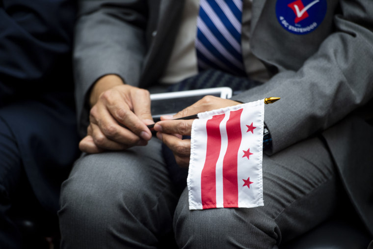 A man holds a Washington, D.C., flag during a House committee hearing on D.C. statehood on Feb. 11, 2020.