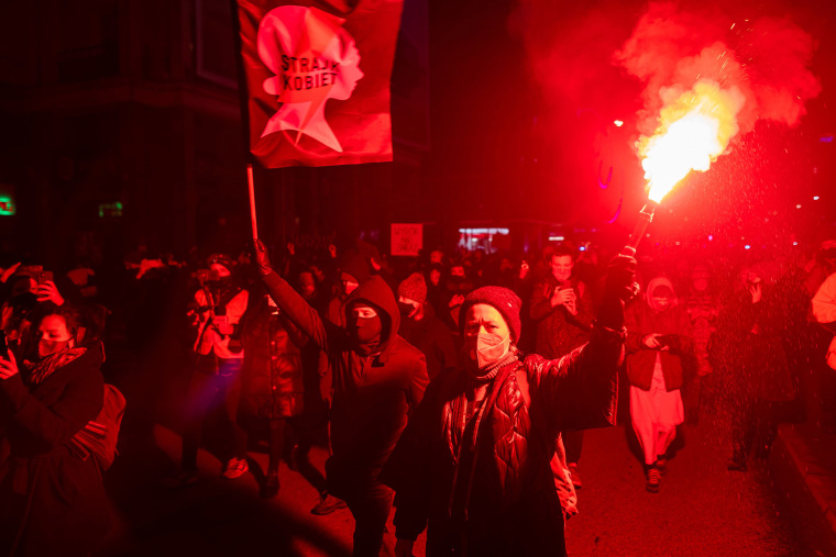 Image: A demonstrator holds a flare as she take part in a pro-choice protest in the center of Warsaw