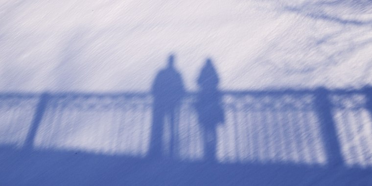 Shadow silhouette of couple man and woman standing on a bridge on snow background on sunny winter day