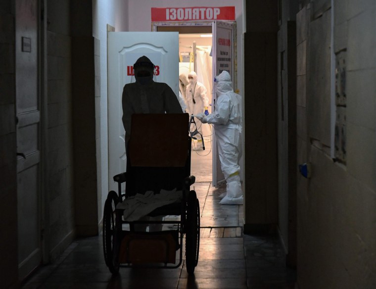 Image: A medical worker pushes a wheelchair along a hall in front of the entrance to the red zone at an infectious diseases department of the Kiev city clinical hospital