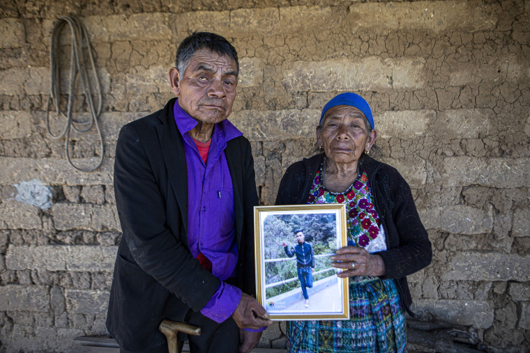 Image: German and Maria Tomas pose for a photograph holding a framed portrait of their grandson Ivan Gudiel, at their home in Comitancillo, Guatemala