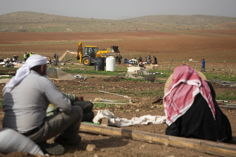 Image: Palestinian Bedouin watch Israeli troops demolish tents and other structures of Khirbet Humsu hamlet in Jordan Valley in the West Bank