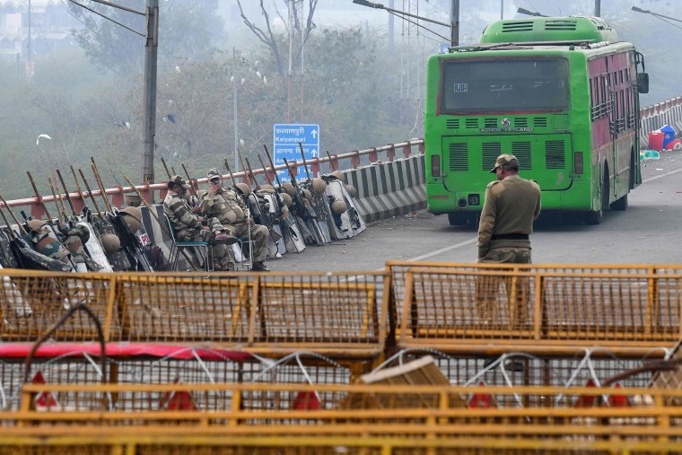 Image: Security personnel sit next to police barricades along a blocked highway as farmers continue to protest against the central government's recent agricultural reforms at the Delhi-Uttar Pradesh state border in Ghaziabad, India