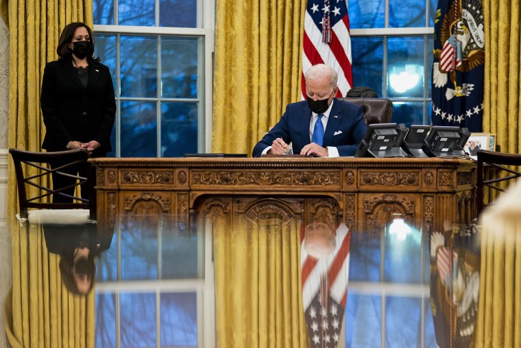 Image: President Joe Biden signs several executive orders directing immigration actions for his administration as Vice President Kamala Harris looks on in the Oval Office at the White House on Feb. 2, 2021.