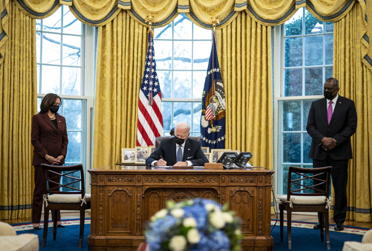 Image: President Joe Biden signs an executive order repealing the ban on transgender people serving openly in the military in the Oval Office.