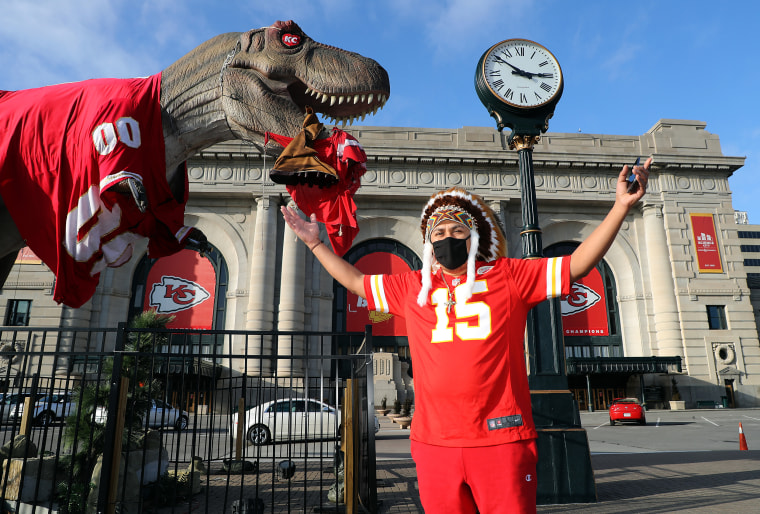 Image: Kansas City Chiefs fan in front of a T-rex statue ahead of Super Bowl LV