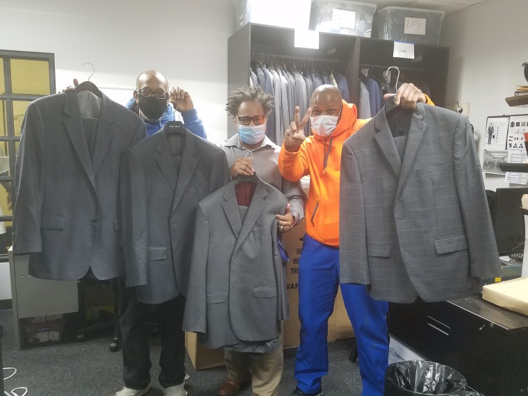 Trainees from The Doe Fund's Ready, Willing and Able program, (r-l) Michael Smith, Joseph Calhoun and George Thomas, receive the donated wardrobe.