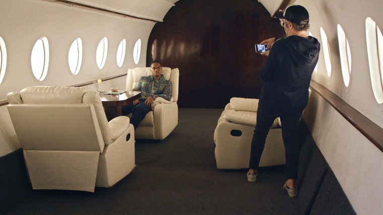 Chris Bailey poses on a set made to resemble the interior of a private jet.