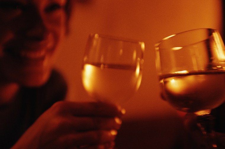 Young couple raising wine glasses, close-up (orange tone)