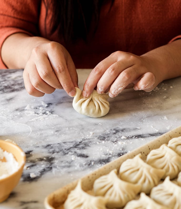 Close up photo of hands folding dumplings with the standard fold.