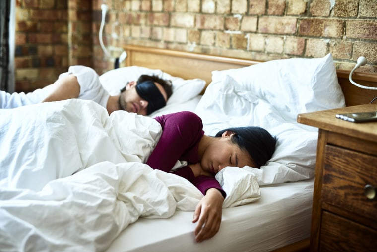 Woman asleep with hand on mattress and man wearing eye mask, The best Presidents Day mattress sales of 2021 according to Consumer Reports include deals from Purple, Casper, Sleep Number, Tempur-Pedic, and more.