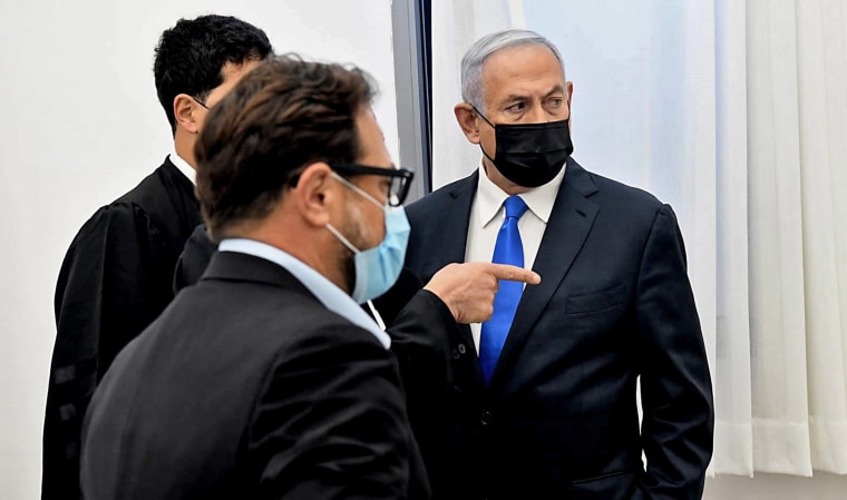 Image: Israeli Prime Minister Benjamin Netanyahu talks to his lawyers ahead of a hearing in his corruption trial at the Jerusalem district court