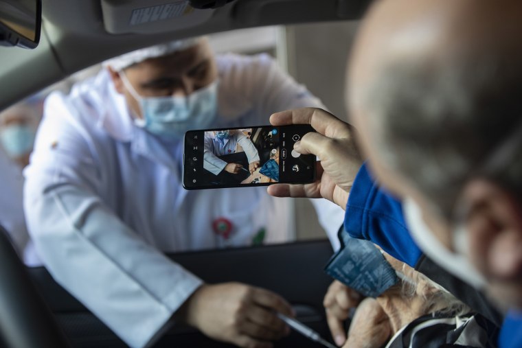 Image: A man photographs his mother getting a shot of China's Sinovac CoronaVac vaccine for Covid-19 during a priority vaccination program for the elderly at a drive-thru site set up in the Pacaembu soccer stadium parking lot in Sao Paulo