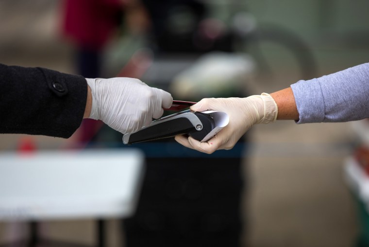 Image: A customer uses a bank card to make a contactless payment on a market stall.