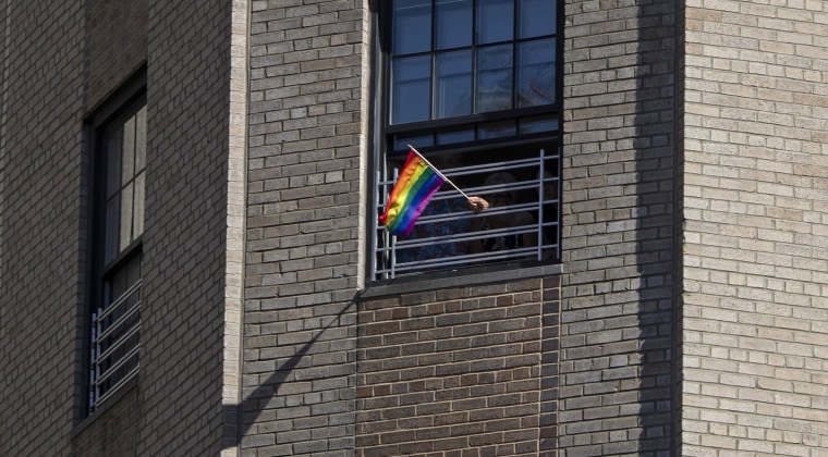 A rainbow flag is waved through window grills in an apartment overlooking the LGBTQ Pride march on June 30, 2019, in New York.