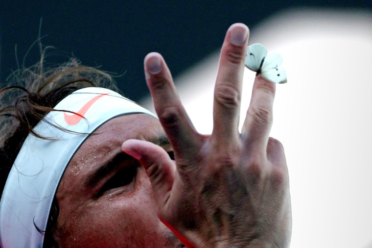 Image: Spain's Rafael Nadal tries to make a butterfly fly from his hand during his first round match against Serbia's Laslo Djere during the Australian Open at Melbourne Park in Australia on Feb. 9, 2021.