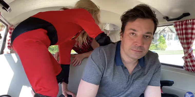 In a blue polo, Jimmy Fallon deadpans to the camera as his two young daughters climb on top of him