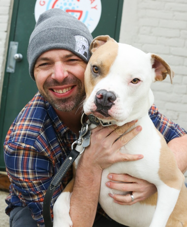 Greg Murray hugs a pit bull.