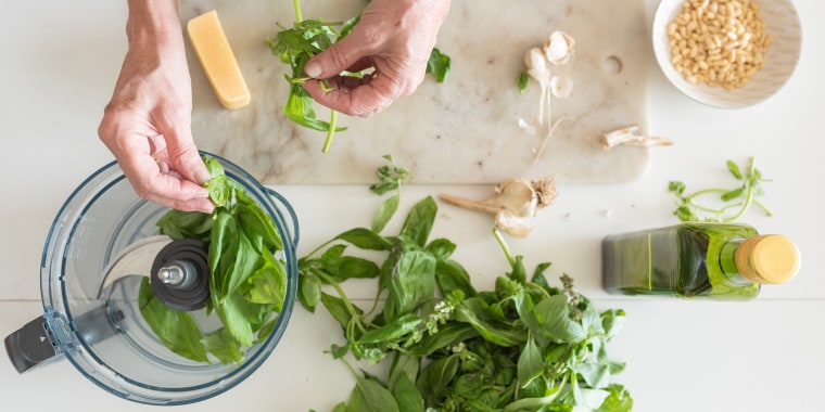 Woman's hands preparing basil for pesto from above