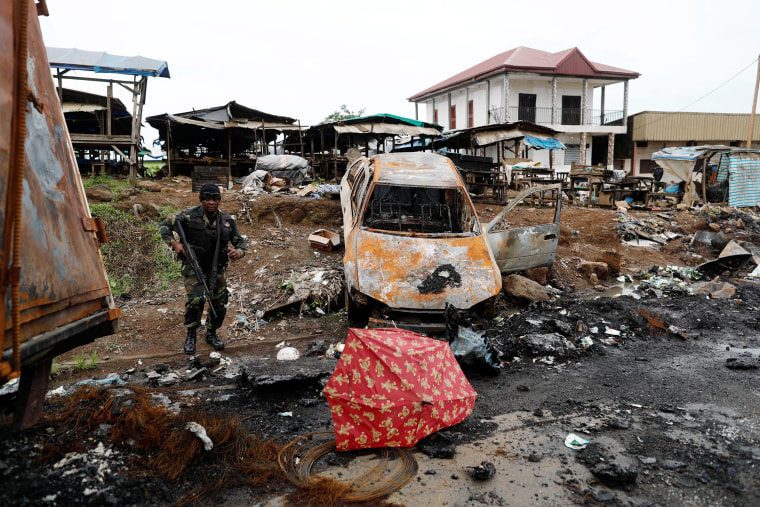 A Cameroonian elite Rapid Intervention Battalion (BIR) member walks past a burnt car while patroling in the city of  Buea in the anglophone southwest region, Cameroon