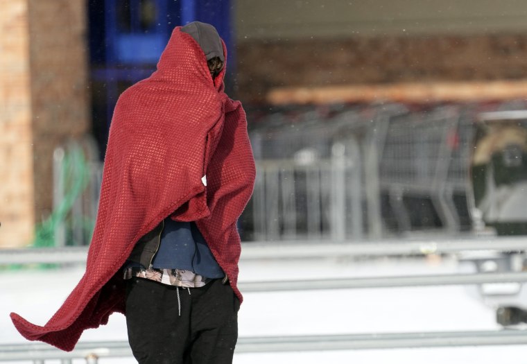 Image: A man peers out from under a blanket while trying to stay warm in below freezing temperatures in Houston