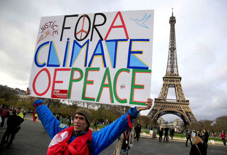 An activist holds a poster during a demonstration near the Eiffel Tower in Paris, during the COP21, the United Nations Climate Change Conference that created Paris climate agreement, on Dec. 12, 2015.