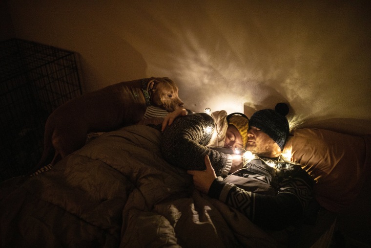 Image: A couple wears multiple layers of clothing under sleeping bags to keep warm at their home in Austin, Texas, on Feb. 18, 2021.