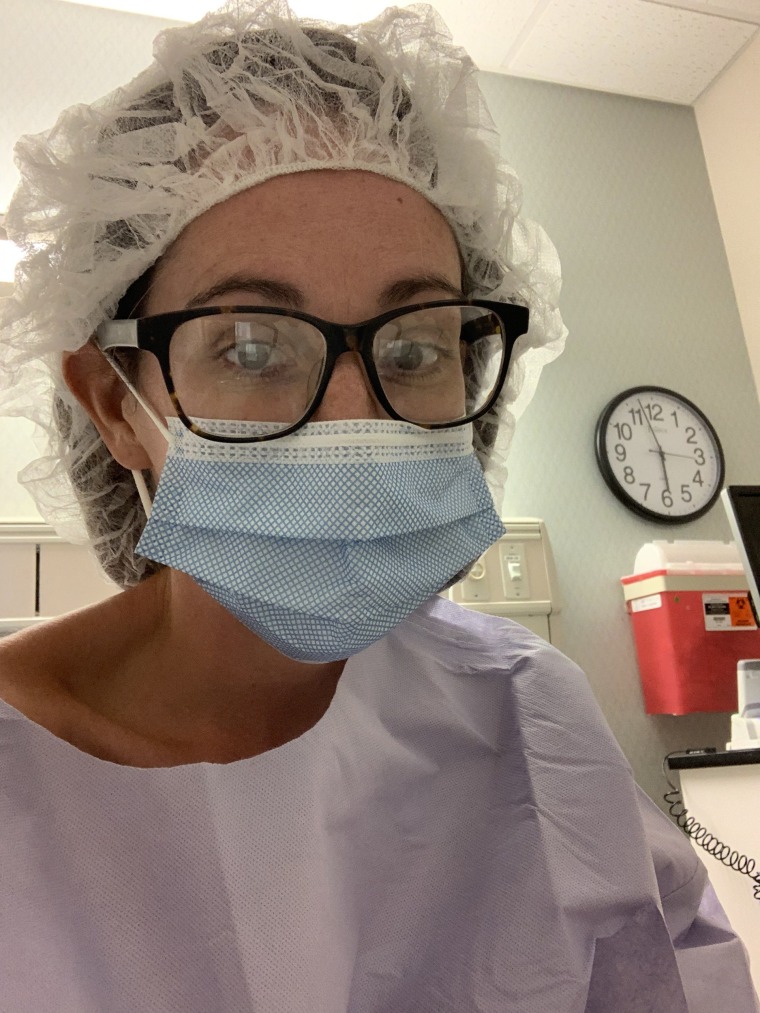 in hospital scrubs, glasses and a facemask, Kaitlin Hanson looks at the camera