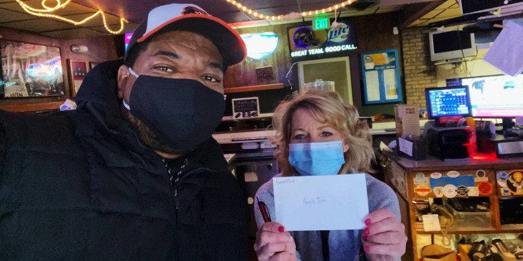 T.J. Smith presents a "Famous Fund" check to a Baltimore restaurant owner.