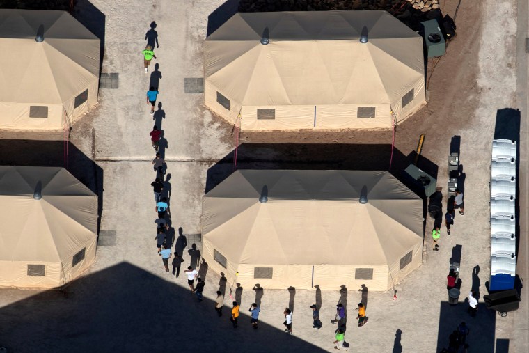 Image: Immigrant children are led by staff in single file between tents at a detention facility in Tornillo, Texas
