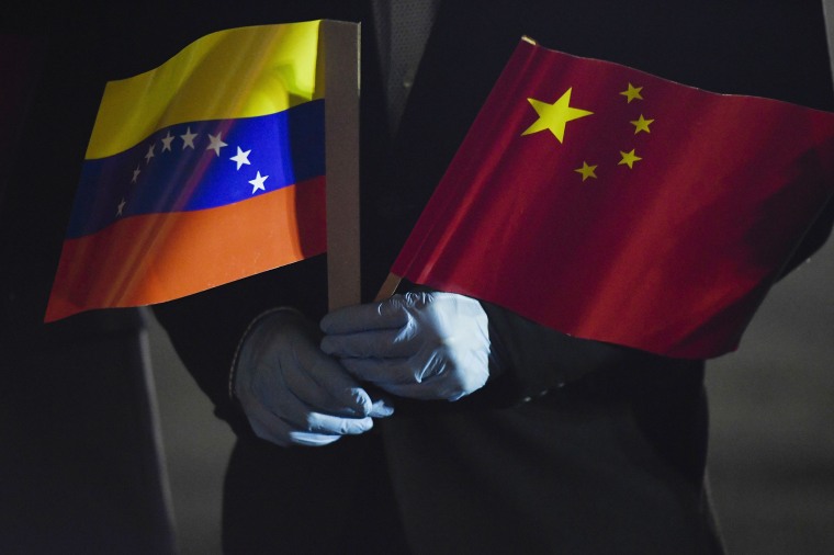 Image: Venezuela's Foreign Minister Jorge Arreaza holds a Venezuelan and Chinese flag as medical specialists and supplies arrive from China