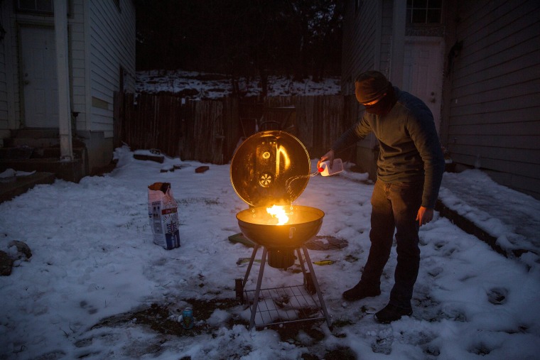 Image: Max King cooks a pizza on a charcoal grill, which he'd purchased earlier in the day, after winter weather caused electricity blackouts in San Marcos, Texas