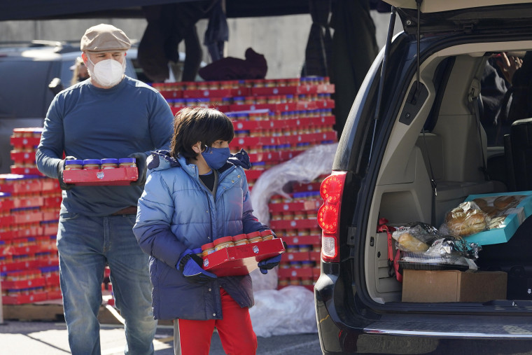 Image: Volunteers hand out food and water at a drive-through food distribution site in San Antonio