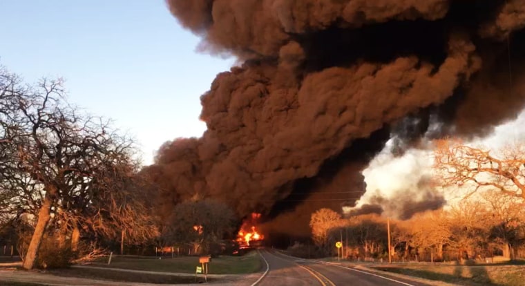 Smoke billows from a fire following an explosion caused by a crash between a train and an 18-wheeler near Cameron, Texas, on Feb. 23, 2021.