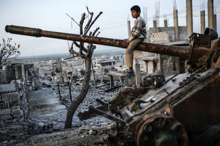 Image: A Syrian Kurdish boy sits on a destroyed tank in the Syrian town of Kobane, also known as Ain al-Arab