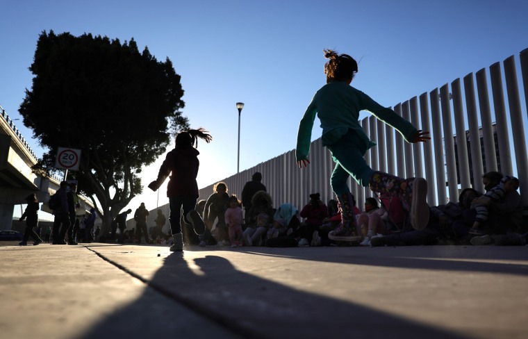 Image: Children play as people who are seeking asylum in the United States are gathered outside the El Chaparral border crossing on Feb. 19, 2021 in Tijuana, Mexico.