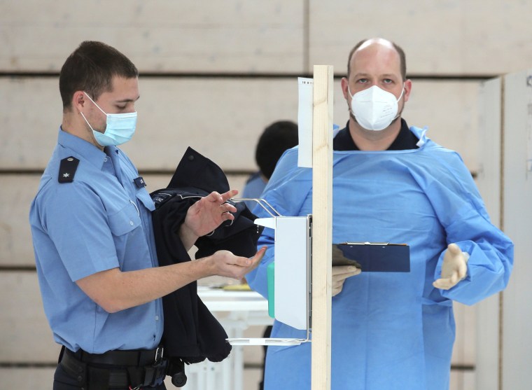 Image: A German police staff member disinfects his hands to receive a dose of AstraZeneca's vaccine against the coronavirus disease (COVID-19) during a vaccination program, in Mainz, Germany