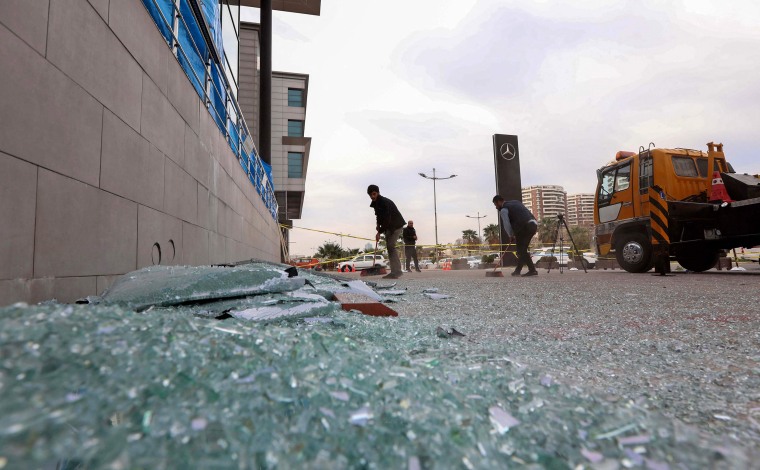 Image: A worker cleans shattered glass outside a damaged shop following a rocket attack the previous night in Irbil, the capital of the northern Iraqi Kurdish autonomous region