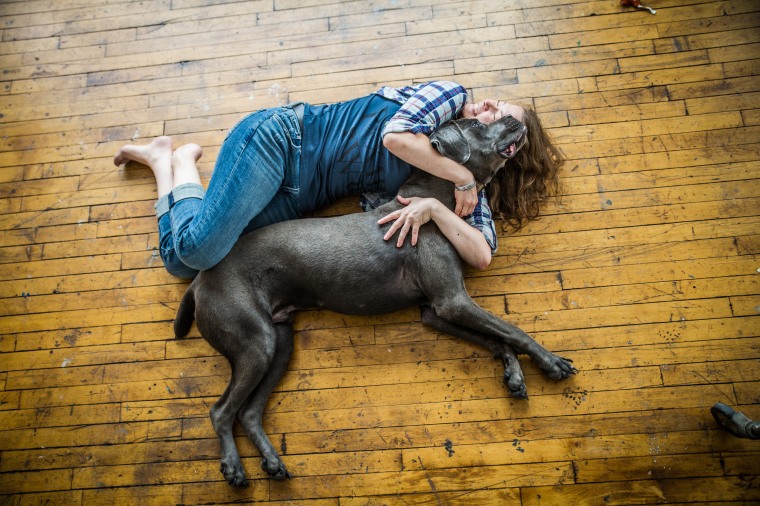 A woman cuddles a Great Dane.