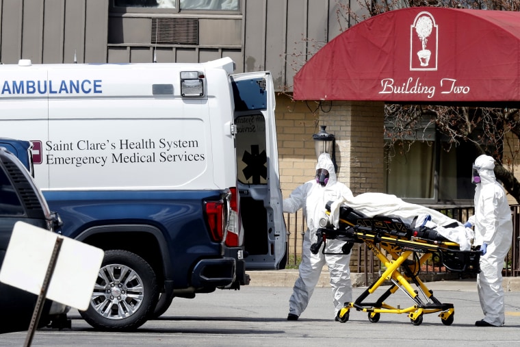 Image: Health care officials prepare to load a patient into an ambulance at Andover Subacute and Rehab Center in Andover, N.J.