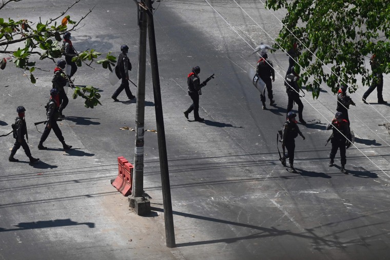Image: Police walk along a road as protesters take part in a demonstration against the military coup in Yangon, Myanmar