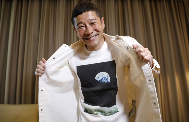 Image: Japanese billionaire Yusaku Maezawa poses with his T-shirt bearing an image of Earth during an interview
