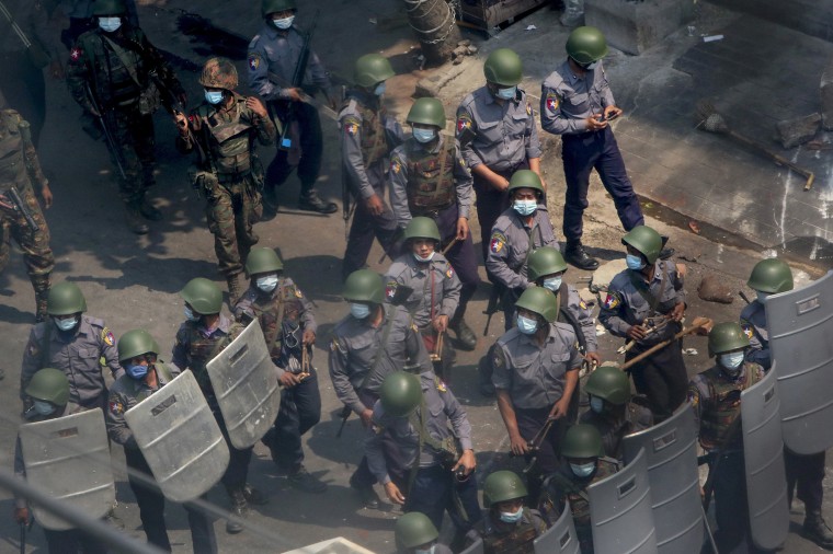 Image: Policemen and soldiers armed with guns and sling-shots advance towards anti-coup protesters in Mandalay, Myanmar
