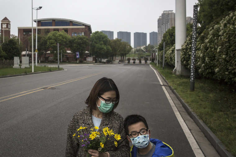 Image: A mother holds flowers while out on a walk with her son on March 31, 2020 in Hubei Province, China. Wuhan,