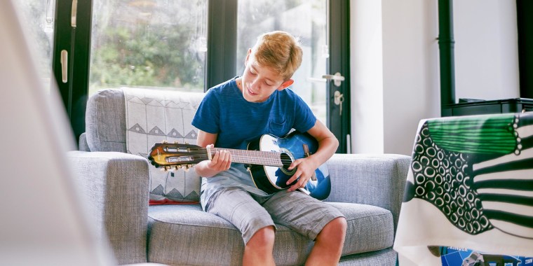 14 year old boy playing on a guitar he got as a gift