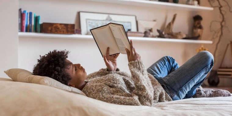 Woman reading a biography book about woman in her bed