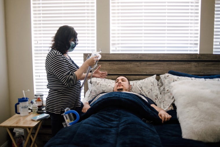 Image: Daysi Marin helps her husband fasten his CPAP machine as he returns to bed