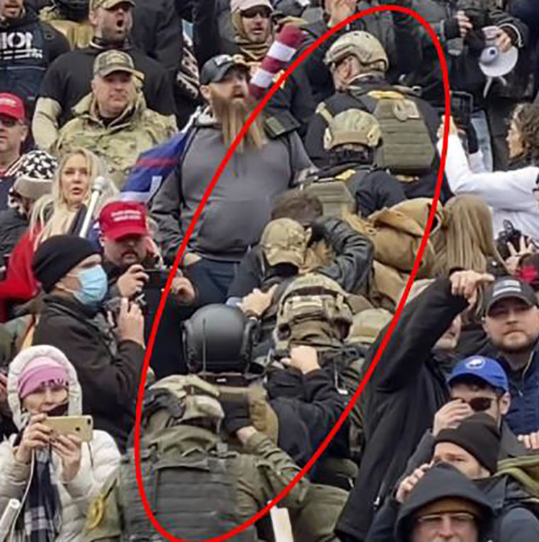 Image: A portion of the \"stack\" of individuals, encircled in red, dressed in matching uniforms consisting of camouflaged-combat attire, moved up and through a crowd on the central staircase on the east side of the U.S. Capitol, according to the affidavit.