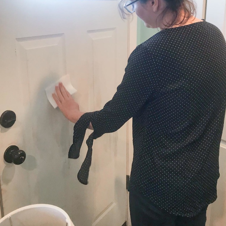 Chrissy Callahan using a Mr. Clean Magic Eraser Multi-Surface Cleaning Sheet on her door, fro Walmart Plus